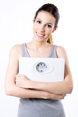 Studio Portrait of beautiful young woman posing with scale